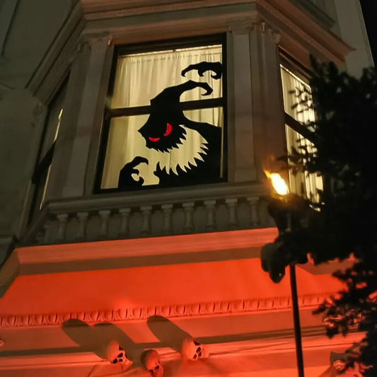 Halloween-themed window display with a black cat silhouette and red eyes on a building exterior. spooky halloween decor